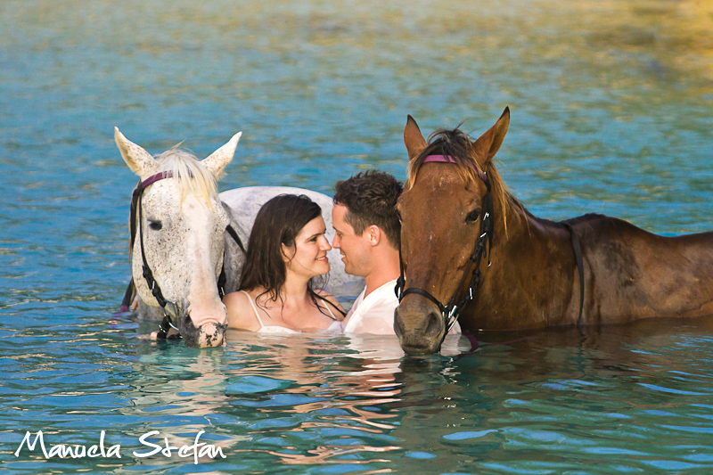 Bride and groom with horses in the ocean